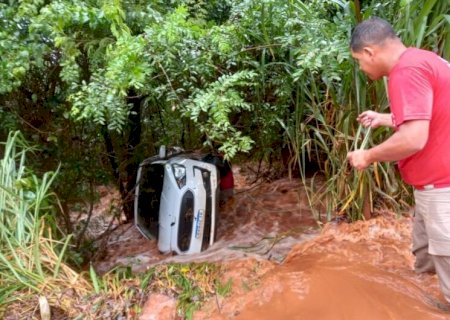 Carro é levado por enxurrada com mulher dentro e vai parar em córrego.